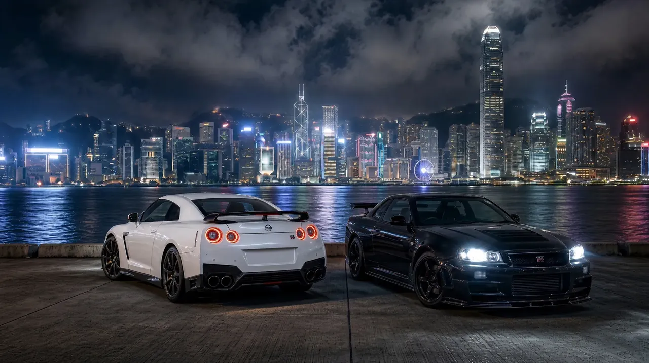 A white R35 GT-R and a black R34 GT-R parked at night in front of a city skyline.